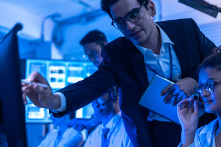 Project manager pointing at computer screen to explain and help team solve software issues